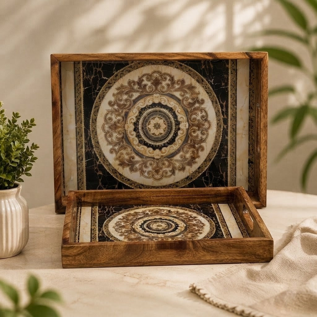 Two decorative wooden serving trays with ornate circular medallion patterns on the inside, displayed on a light beige tablecloth with a small potted plant and draped fabric nearby.