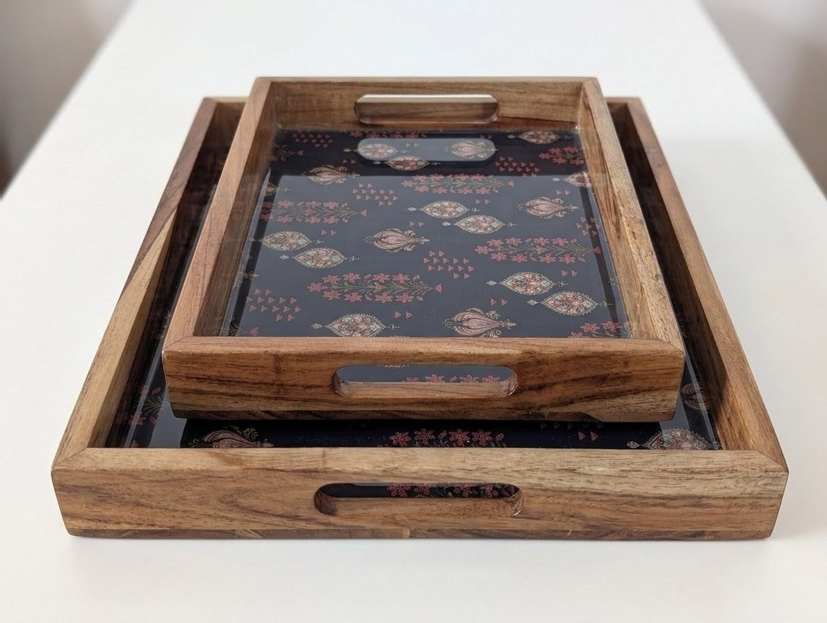 Two nested wooden serving trays with cutout handles, featuring a dark navy and gold patterned liner